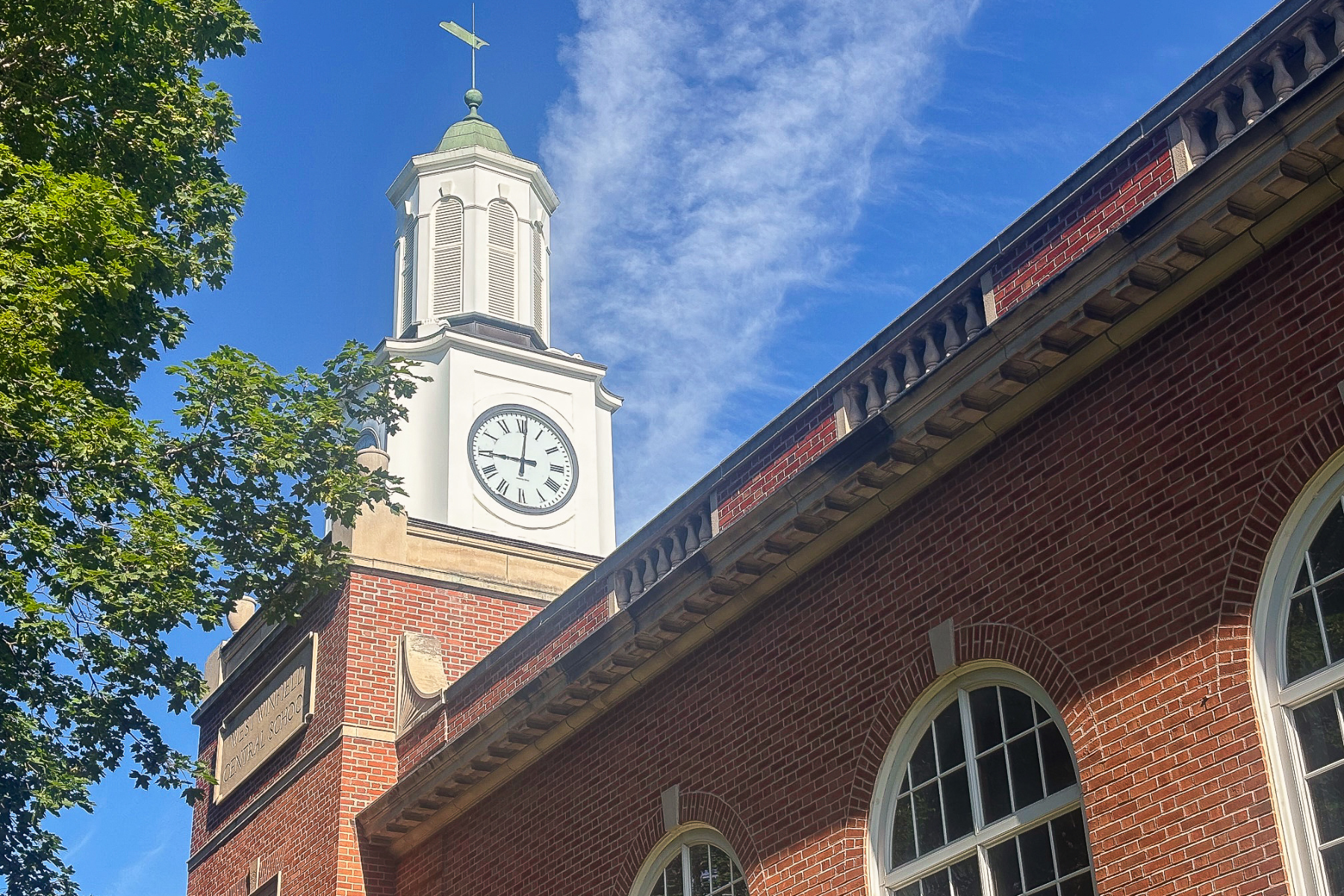 A red brick building featuring a clock tower under a blue sky 